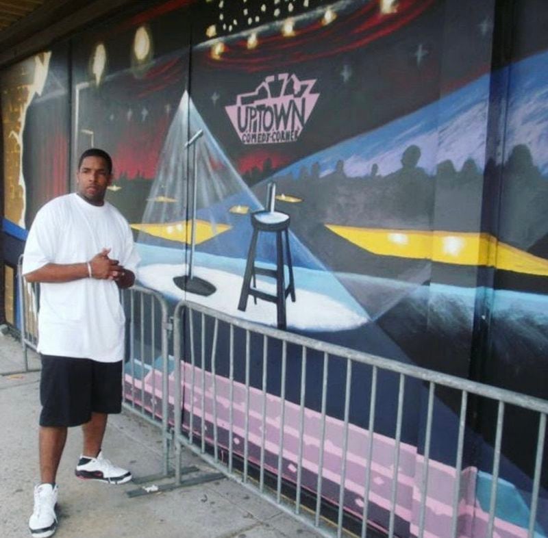 Arshaad Norwood stands in front of the mural he painted on the Uptown Comedy Corner building in 2009. Photo: Courtesy of Arshaad Norwood
