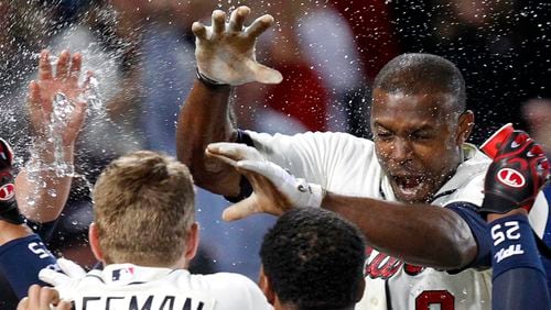 Atlanta Braves' Justin Upton, top right, is doused by teammates as he crosses home plate after hitting a walkoff home run during the ninth inning of a baseball game against the Chicago Cubs, Saturday, April 6, 2013, in Atlanta. Atlanta won 6-5. (AP Photo/Butch Dill)