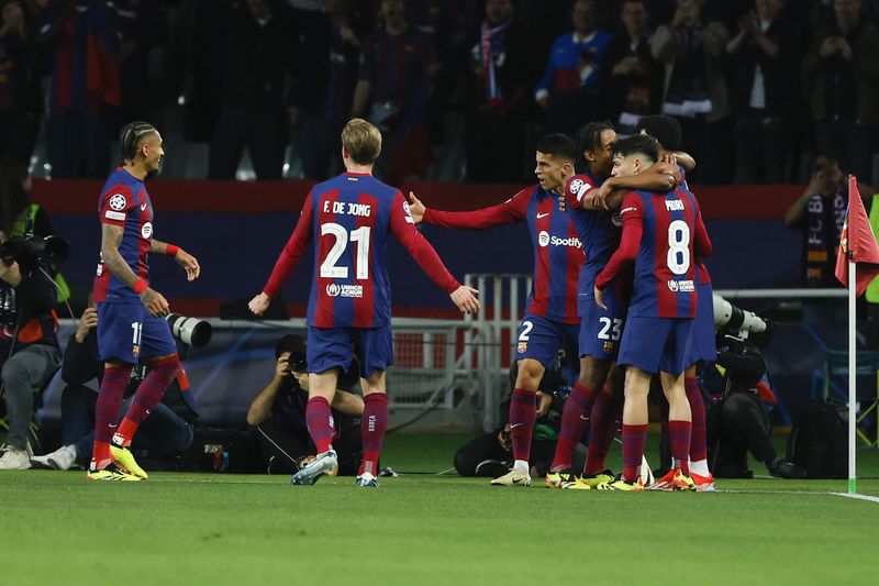 Barcelona's Raphinha, left, celebrates with teammates after scoring the opening goal during the Champions League quarterfinal second leg soccer match between Barcelona and Paris Saint-Germain at the Olimpic Lluis Companys stadium in Barcelona, Spain, Tuesday, April 16, 2024. (AP Photo/Joan Monfort)