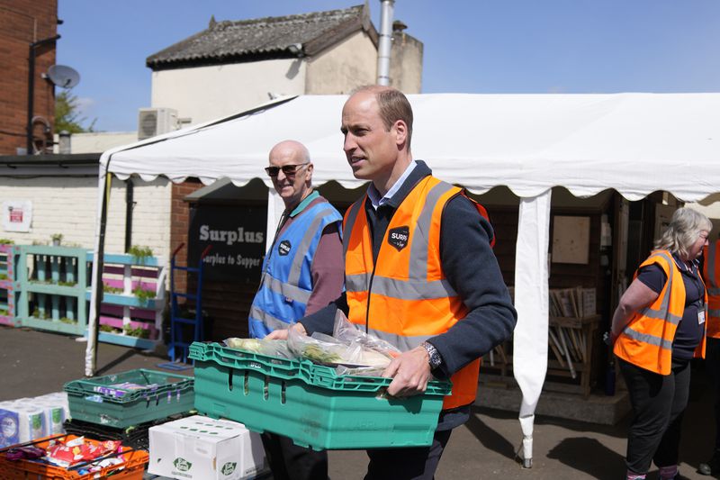 Britain's Prince William helps to loads trays of food into vans during a visit to Surplus to Supper, in Sunbury-on-Thames, Surrey, England, Thursday, April 18, 2024. The Prince visited Surplus to Supper, a surplus food redistribution charity, to learn about its work bridging the gap between food waste and food poverty across Surrey and West London. (AP Photo/Alastair Grant, pool)