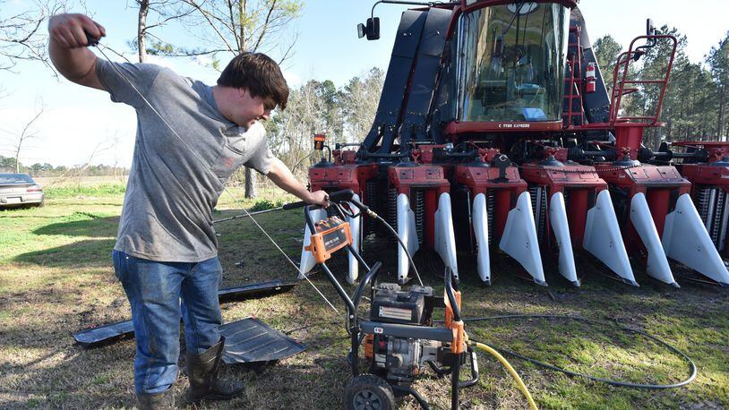 Young farmer Reese Foster prepares to power-wash a gigantic cotton picker earlier this year at his home near Dawson, Georgia. Foster and many other farmers are carrying over debt into 2019 because bad weather ruined crops. Chinese tariffs are also destabilizing the market for cotton, pecans, peanuts and other Georgia crops, which has a broader economic impact on the state. HYOSUB SHIN / HSHIN@AJC.COM