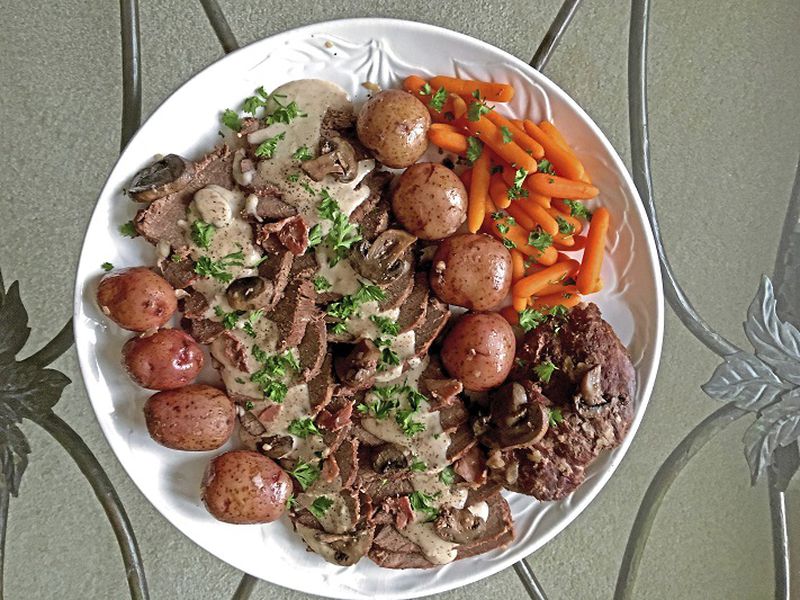Venison with mushrooms in a sour cream gravy, plated with new potatoes and carrots. (Karen Kane/Post-Gazette)
