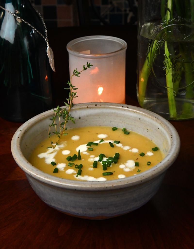 Potato Leek Soup is drizzled with heavy cream and garnished with chopped chives. (Styling by Tatiana Gonzalez / Chris Hunt for the AJC)