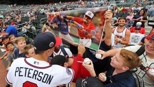 Braves' Jace Peterson signs a poster displayed by fans with his face superimposed on a poster hitting Blue Jays' Jose Bautista.
