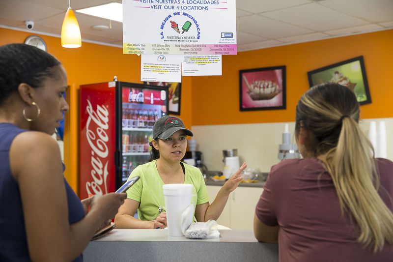 Manager Maritza Cantero (center) helps customers Shandale Brantley (left) and Erica Garcia (right) choose flavored popsicles at La Major de Michoacan, located at 403 Atlanta Highway, in Gainesville. (Alyssa Pointer/alyssa.pointer@ajc.com)