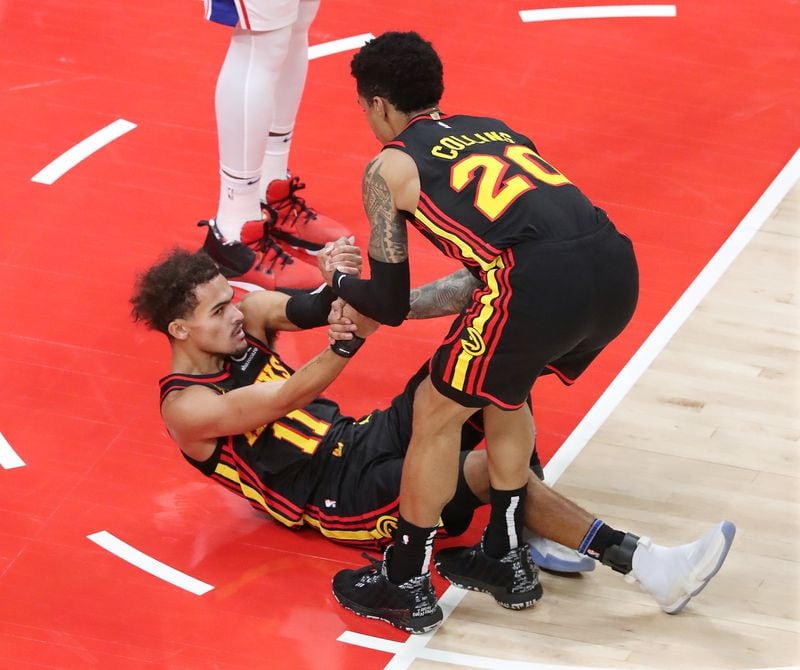 John Collins of the Hawks helps Trae Young up after he was fouled by the Philadelphia 76ers on Monday, Jan. 11, 2021, at State Farm Arena in Atlanta. (Curtis Compton / Curtis.Compton@ajc.com)