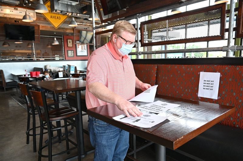 District manager Harry Decker sorts through signs on Saturday, April 25, 2020, for social distancing efforts as restaurant staff prepare to reopen the restaurant at Bad Daddy’s Burger Bar in Decatur. Gov. Brian Kemp announced that movie theaters and restaurant dining rooms can reopen Monday, April 27, following guidelines. 