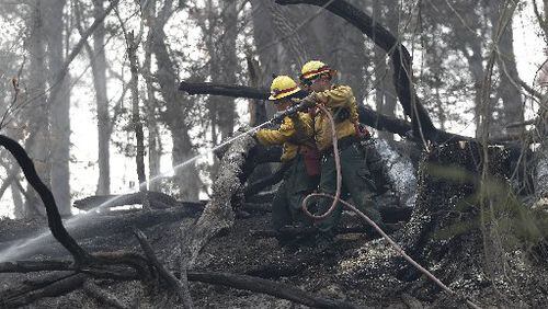 Firefighters Valarie Lopez (left) and Mark Tabaez work to cool hot spots on a hillside in Clayton. (Credit: Associated Press)
