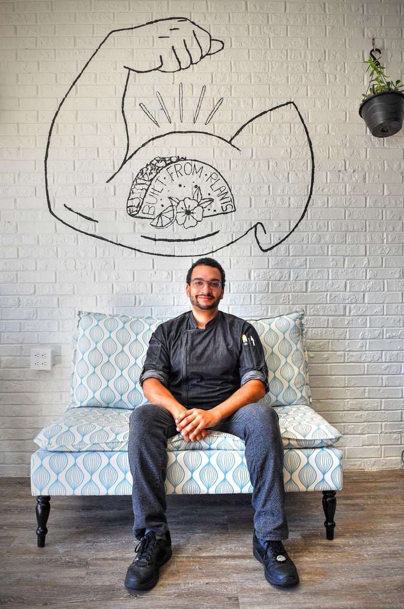 Sitting in front of his own original artwork at Papi Ali's is owner Mikail Ali. He's known as Papi by co-workers and restaurant patrons. (Chris Hunt for The Atlanta Journal-Constitution)