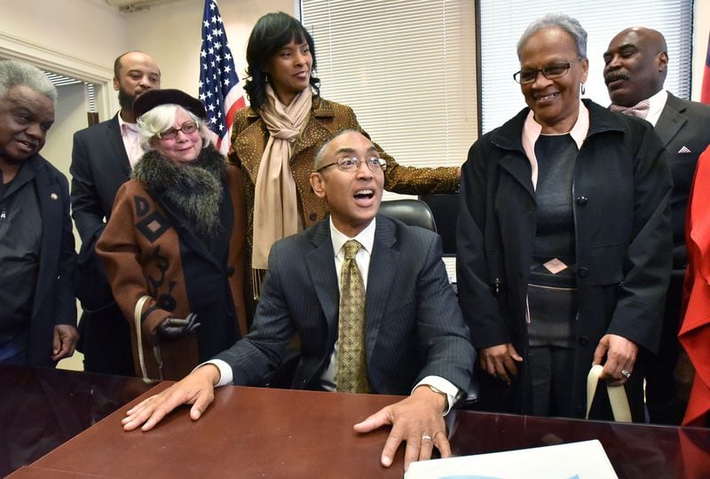 DeKalb County CEO Burrell Ellis, surrounded by his wife Philippa and supporters, takes a seat at his desk on the sixth floor of the county government building in Decatur on Wednesday after he was reinstated to office. HYOSUB SHIN / HSHIN@AJC.COM
