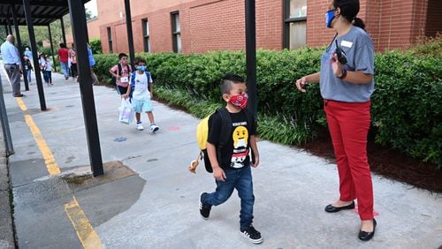 Students wearing masks arrive at Jackson Elementary School in Lawrenceville for the first day of school amid the coronavirus outbreak on Wednesday, Aug. 26, 2020. Gwinnett County, the state’s largest SCHOOL district, publishes a report of coronavirus cases online each weekday. Now, every public school in Georgia will provide information about cases, quarantines and clusters of cases to the Georgia Department of Public Health each Friday as part of a new uniform COVID-19 reporting system. Hyosub Shin / Hyosub.Shin@ajc.com