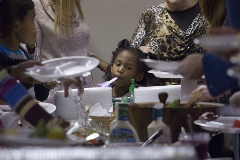 Liana Hill, of First Baptist Church on New Street, middle, looks at her options of food while other parishioners fix their plates at First Baptist Church’s Thanksgiving Potluck on Sunday, Nov. 19.