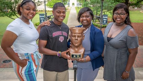 Shanoca French and her three children, Madison (L), Alex, and Alexis (R), stand around a bust of her husband, Alex French, at the Georgia Military College Preparatory School in Milledgeville Wednesday, May 24, 2022. The bust was made by Cliff Leonard, who creates busts of veterans for free as a service to others. (Steve Schaefer / steve.schaefer@ajc.com)