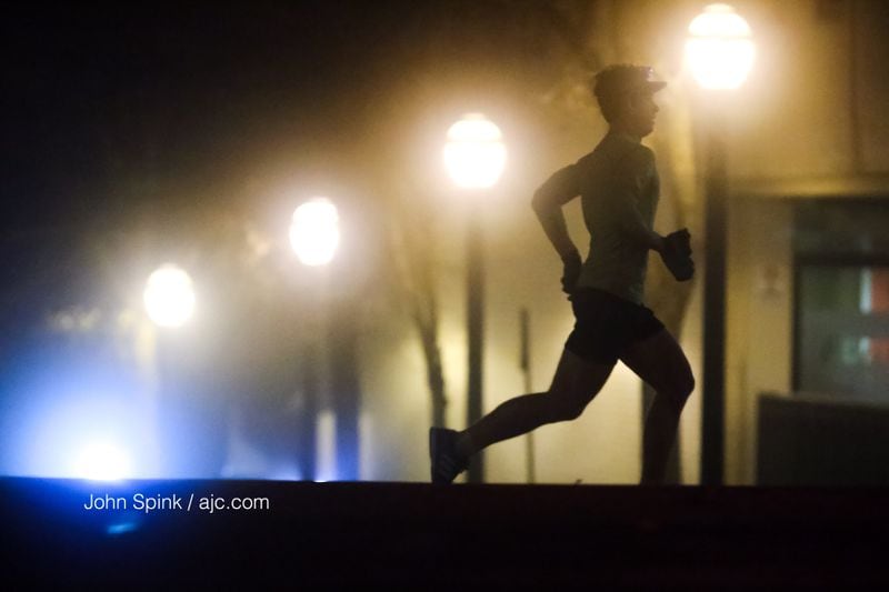 Ross Kimbel runs along Peachtree Street at 17th Street, getting in 12 miles in the fog. JOHN SPINK / JSPINK@AJC.COM