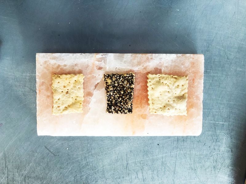  Three varieties of Georgia Sourdough crackers sit atop a salt slab. Left to right, they are cheese, everything, and plain. /Jr Marranci