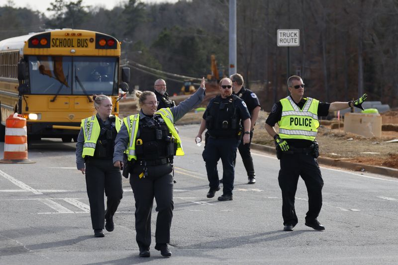 Cobb County officers block traffic for buses from McEachern High School to keep moving Thursday.