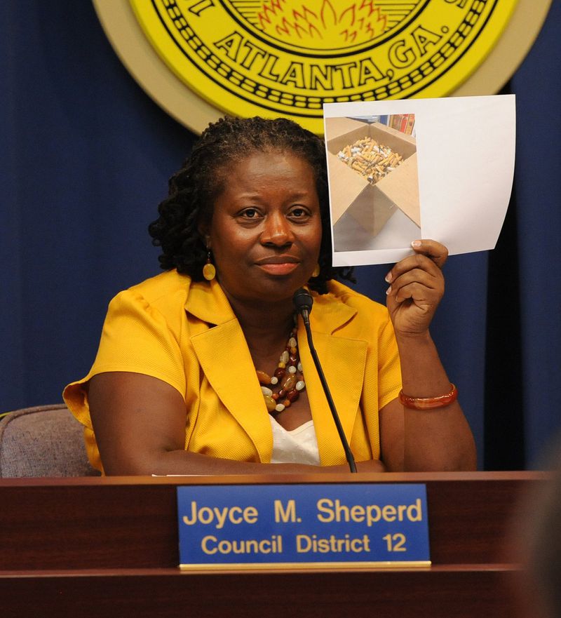 Atlanta City Council member Joyce Sheperd holds up a photo of cigarette butts collected from Atlanta parks during a committee meeting in 2012 about banning smoking in parks. JOHNNY CRAWFORD / JCRAWFORD@AJC.COM