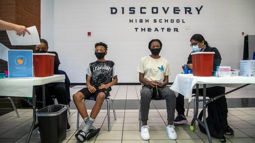 In this file photo, siblings Jared McCauley, 14, second from left, and Maya McCauley, 15, second from right, wait to receive the Pfizer COVID-19 vaccine during a free vaccination event held by the Gwinnett, Newton, Rockdale County Health Department at Discovery High School in Lawrenceville. (Alyssa Pointer/Atlanta Journal Constitution)