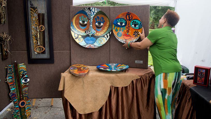 Artist Sylvia Cohen adjusts one of her paintings during the ninth annual Piedmont Park Arts Festival on Saturday, August 18, 2018. STEVE SCHAEFER / SPECIAL TO THE AJC