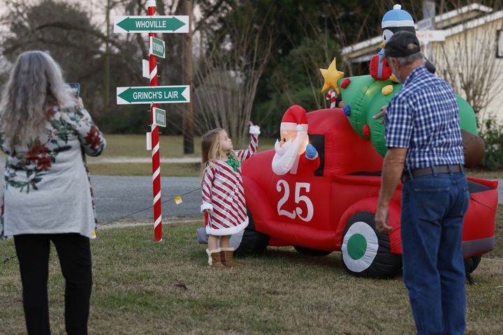Santa Claus City council member Renee Wright tries to take a photo of her granddaughter Alayna Jernigan as her husband, Walter Wright, looks at one of the intersections decorated with candy cane stripes and inflatable decorations. Miguel Martinez / miguel.martinezjimenez@ajc.com
