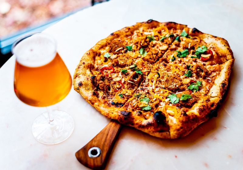 Food options abound at brewing operations, and even pizzas often aren’t run-of-the-mill anymore. Here, a pizza topped with Thai chile sausage, peanut sauce, pickled peppers and cilantro is paired with a house-brewed beer at Bold Monk Brewing. CONTRIBUTED BY HENRI HOLLIS