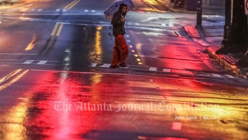 Jason Scott crosses Peachtree Street near Auburn Avenue in the rain Tuesday morning.