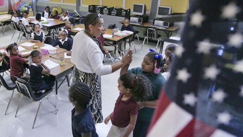 First grade teacher Marta Troutman high-fives students who lined up correctly at the DeKalb Elementary School of the Arts. The school will now be known as DeKalb Arts Academy. (AJC file photo)