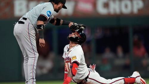 Orlando Arcia is playfully tagged on the head by Marlins second baseman Luis Arraez (3) after sliding into second base with a double in the seventh inning of Monday's Braves-Marlins game at Truist Park.  (AP Photo/John Bazemore)