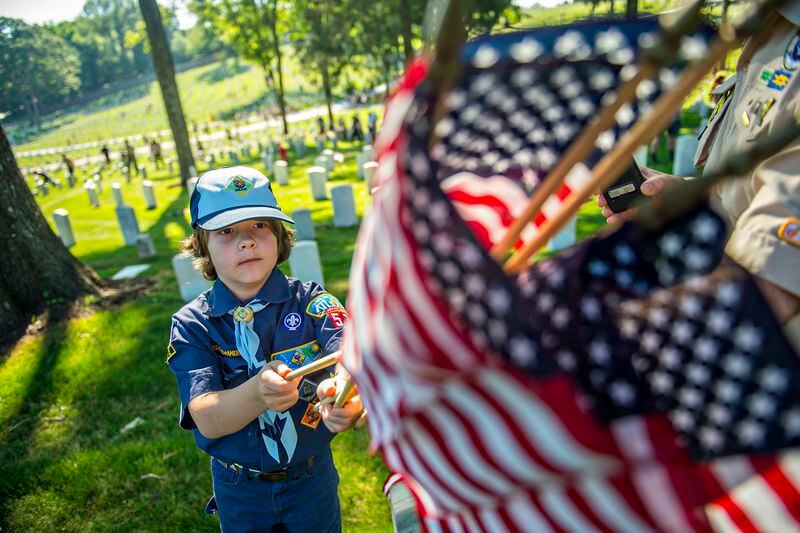May 23, 2015 Marietta - Austin Hampson (left) grabs his next flag to place at one of the graves in the Marietta National Cemetery on Saturday, May 23, 2015. Hundreds of Boy Scouts, Girl Scouts and Cub Scouts placed flags on the 18,500 soldiers' grave stones in preparation for the Memorial Day service on Monday. JONATHAN PHILLIPS / SPECIAL