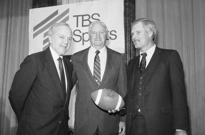 Ted Turner, right, holds a football at a news conference, Wednesday, April 11, 1985, New York. At left is Bob Wussler, Super Station WTBS president and Robert C. James, Atlantic Coast Conference commissioner, center. Turner Broadcasting System, Inc. and the Big Ten, Pacific-10 and Atlantic Coast Conferences announced a two-year agreement for live coverage of collage football games during prime-time for the 1985 and 1986 season on cables Super Station WTBS. (AP Photo/Paul Burnett)