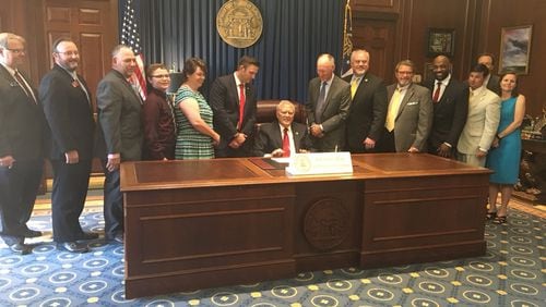 Gov. Nathan Deal signed House Bill 65 into law Monday to add PTSD and intractable pain to the list of conditions treatable by cannabis oil. State Rep. Allen Peake, the sponsor of the bill, is on Deal's right. They're surrounded by legislators and supporters. Photo credit: State Rep. Allen Peake