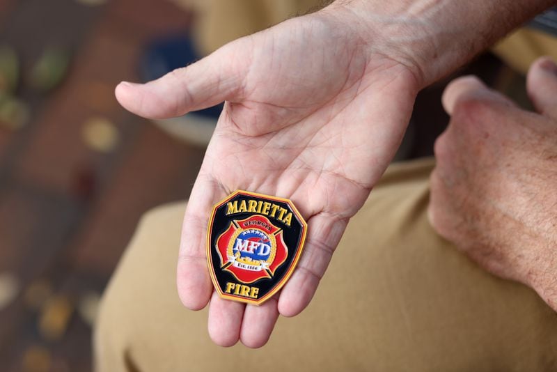Former Marietta Firefighter Webb Smith holds the medal he received for being the 2020 Firefighter Engineer of the Year, shown at the Marietta Square, Thursday, November 3, 2022, in Marietta, Ga. Smith resigned after 15 years of service. (Jason Getz / Jason.Getz@ajc.com)