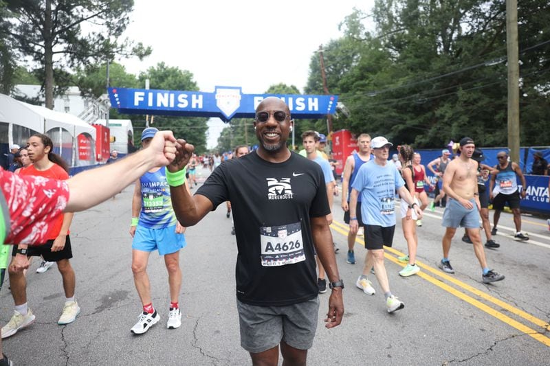 Sen. Raphael Warnock celebrates at the finish of the 54th running of the Atlanta Journal-Constitution Peachtree Road Race in Atlanta on Tuesday, July 4, 2023.  (Jason Getz/The Atlanta Journal-Constitution)