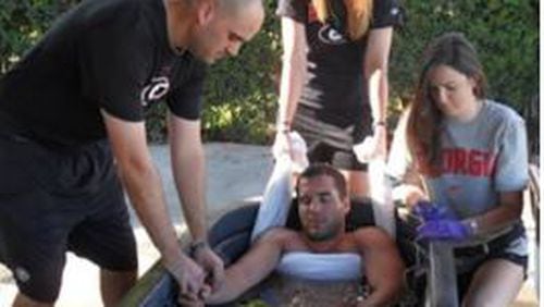 University of Georgia staff and students simulate use of a cold immersion tub to treat heat exhaustion and heat stroke. The towel under the arms keeps the victim from drowning.