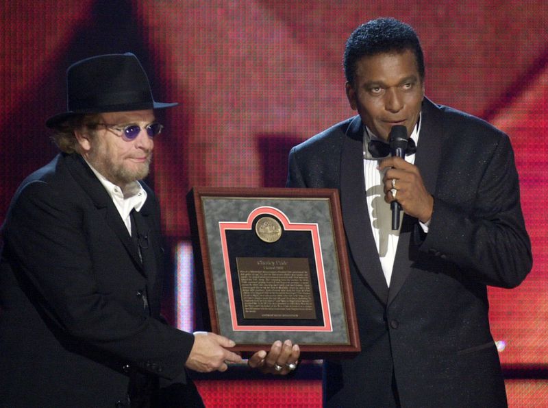 Charley Pride, right, receives his Country Music Hall of Fame plaque from Merle Haggard at the Country Music Association Awards show at the Grand Ole Opry House in Nashville, Tennessee, on October 4, 2000. (AP Photo/Charlie Neibergall, File)