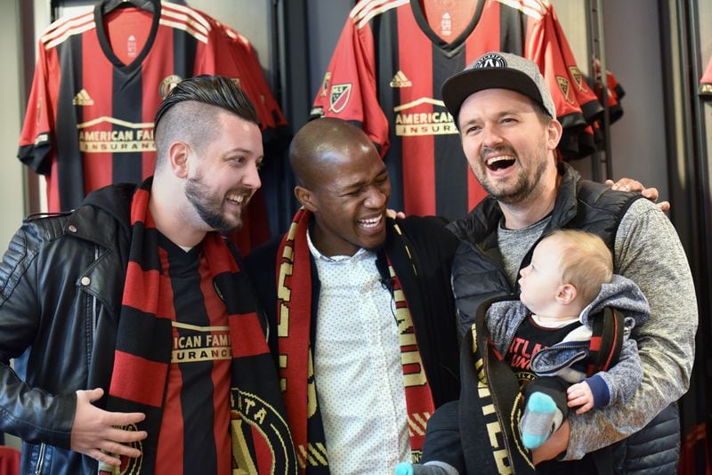 December 15, 2017 Atlanta - New Atlanta United midfielder Darlington Nagbe shares a smile with fans Adam Boyle (left) and Andrew Amerson with his son Elon, 6-months, as they pose for a group photograph at the Team Store at Mercedes-Benz Stadium on Friday, December 15, 2017. Atlanta United introduced midfielder Darlington Nagbe to the media Friday at Mercedes-Benz Stadium. Hyosub Shin / hshin@ajc.com