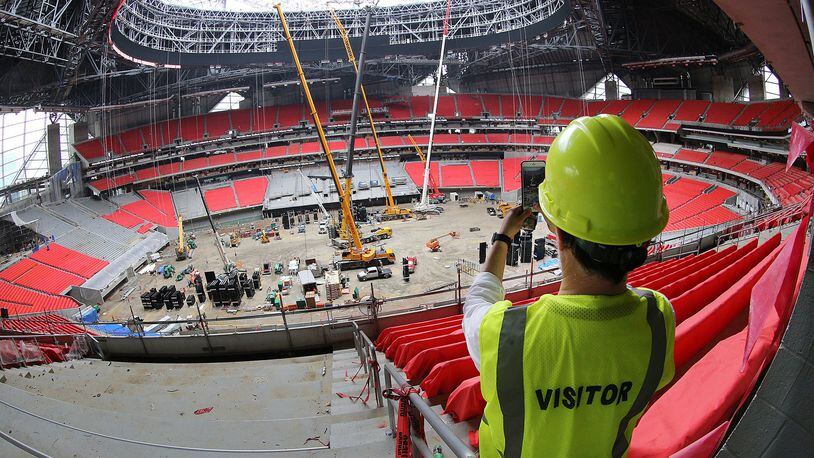 On a Thursday tour of Mercedes-Benz Stadium, a visitor snaps a photo showing many seats installed and the installation of panels for the halo-shaped video board underway. (Curtis Compton/ccompton@ajc.com)