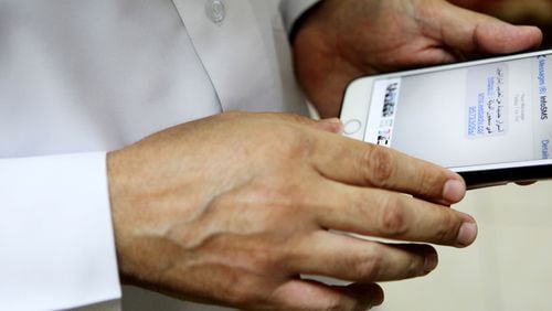 Human rights activist Ahmed Mansoor shows Associated Press journalists a screenshot of a spoof text message he received in Ajman, United Arab Emirates, on Thursday, Aug. 25, 2016. Mansoor was recently targeted by spyware that can hack into Apple's iPhone handset. The company said Thursday it was updated its security. The text message reads: "New secrets on the torture of Emirati citizens in jail." (AP Photo/Jon Gambrell)