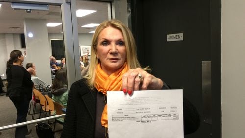 Perri Higbie shows a $795,458 water bill that her Brookhaven homeowners' association received from DeKalb County in August. Higbie and about 100 residents attended a water billing community meeting on Nov. 2, 2015. MARK NIESSE / MARK.NIESSE@AJC.COM