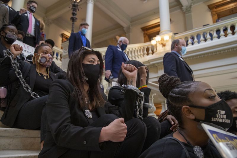 Demonstrators chain themselves together as they stage a sit-in protest against election legislation during Crossover Day. (Alyssa Pointer / Alyssa.Pointer@ajc.com)