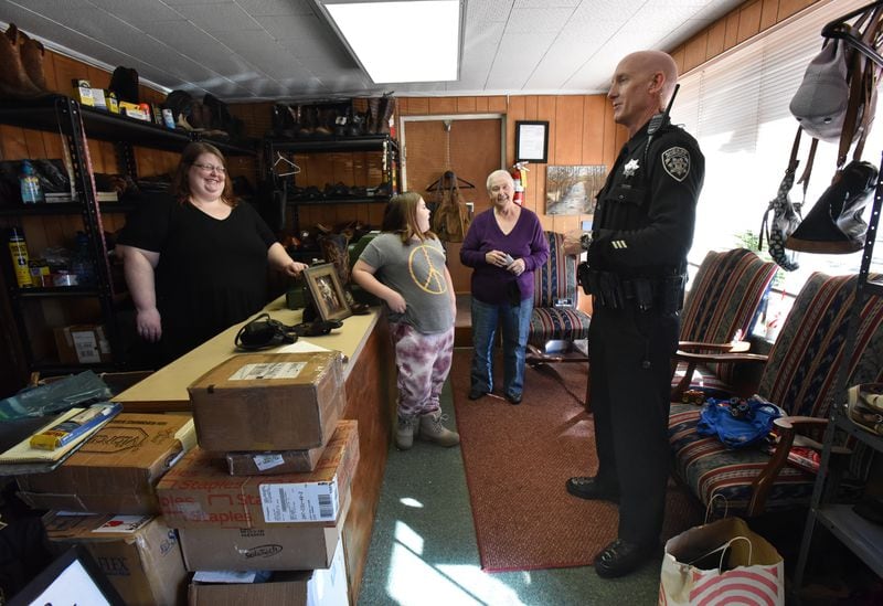 Brittany Morgan, left, assists Brian Venable, a Cherokee County deputy sheriff, with her 8-year-old daughter, Peyton, second from left, and grandmother, Ruth Moss, at Canton Shoe Repair. Venable, wearing shoes Billy Moss repeatedly repaired, was a longtime customer. (Hyosub Shin / Hyosub.Shin@ajc.com)