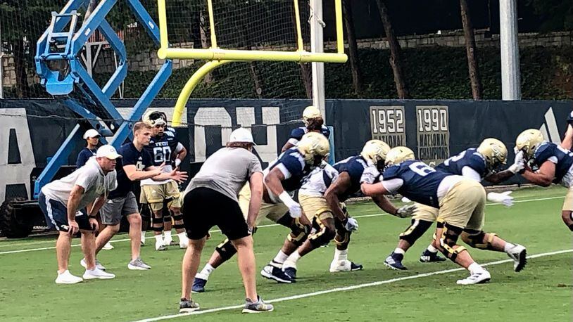 Georgia Tech offensive line coach Brent Key (left, hands on knees) oversees a drill at a practice. (AJC photo by Ken Sugiura)