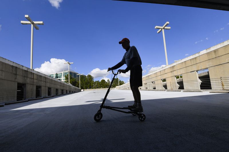 L.H. Couch a 76-year-old retired IT executive, rides his exercise Trikke on an empty level of an office parking deck in Sandy Springs. Many metro Atlanta employees are still working from home after corporate offices shutdown early in the pandemic. That's left plenty of open space for Couch. JOHN AMIS FOR THE ATLANTA JOURNAL-CONSTITUTION