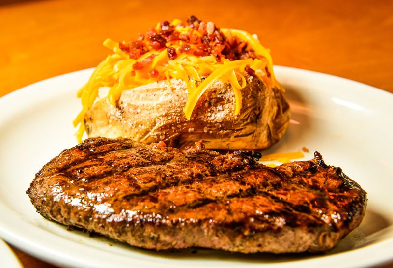 An 11-ounce hand cut sirloin with loaded baked potato at Texas Roadhouse on Kingsgate Way in West Chester Twp. NICK GRAHAM/STAFF