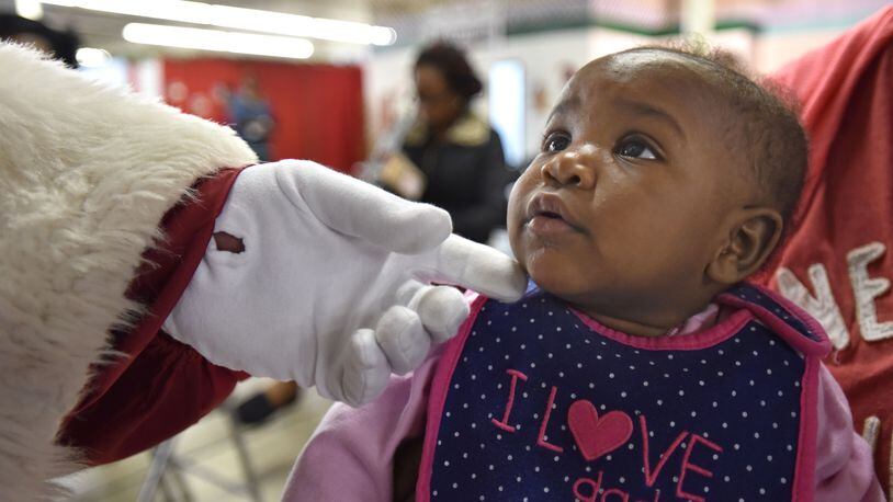 From Dec. 1, 2015: Seven-month-old Kailin Wright looks up Santa Claus (George Wieder) as he touches her cheek at Santa's Village in Atlanta. Each year, parents and guardians of more than 40,000 children come to Santa's Village to select gift items for their children. Santa's Village is The Empty Stocking Fund's gift distribution center for Fulton and DeKalb counties.