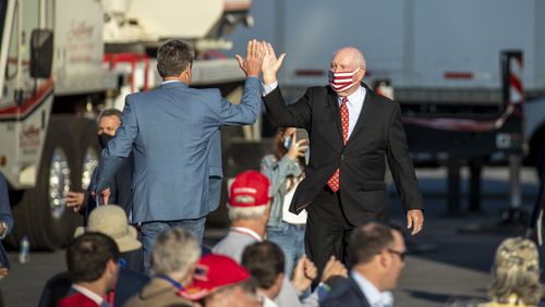 U.S. Secretary of Agriculture Sonny Perdue (right) give Gov. Brian Kemp a high five as he prepares to make remarks at a President Donald Trump rally at Middle Georgia Regional Airport in Macon, Friday, October 16, 2020.  (Alyssa Pointer / Alyssa.Pointer@ajc.com)