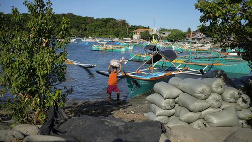 A resident brings down a sack from his boat at the coastal town of Santa Ana, Cagayan province, northern Philippines on Tuesday, May 7, 2024. The United States and the Philippines, which are longtime treaty allies, have identified the far-flung coastal town of Santa Ana in the northeastern tip of the Philippine mainland as one of nine mostly rural areas where rotating batches of American forces could encamp indefinitely and store their weapons and equipment within local military bases under the Enhanced Defense Cooperation Agreement, or EDCA. (AP Photo/Aaron Favila)