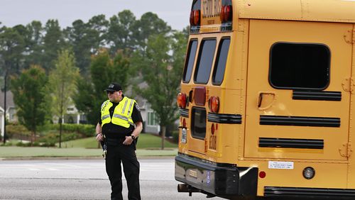 A police school crossing guard directs traffic at the entrance of Kemp Elementary School on the first day of school on Monday, Aug. 1, 2022. Cobb County wants to provide raises for its bus drivers. (Natrice Miller/natrice.miller@ajc.com)