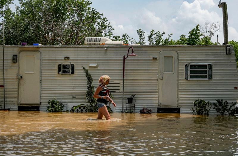 A woman, who only gave her name as Lisamarie, checks on an elderly resident inside his RV after their neighborhood was evacuated due to severe flooding, Saturday, May 4, 2024, in Channelview, Texas. (Raquel Natalicchio/Houston Chronicle via AP)