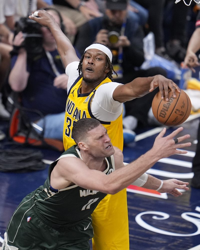 Indiana Pacers' Myles Turner (33) defends Milwaukee Bucks' Brook Lopez (11) during the second half of Game 4 of the first round NBA playoff basketball series, Sunday, April 28, 2024, in Indianapolis. (AP Photo/Michael Conroy)